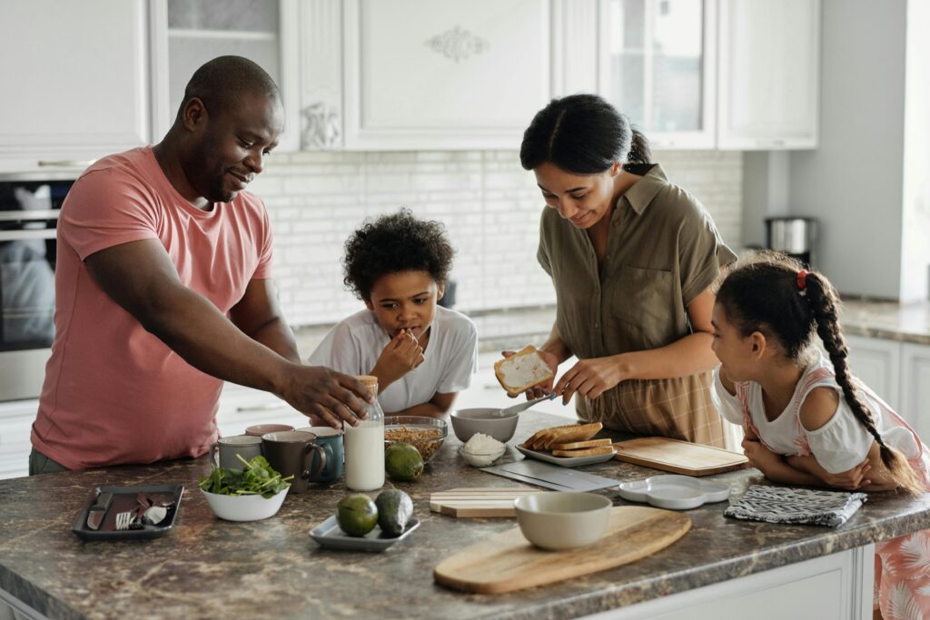 A mother and father in the kitchen with their 2 kids